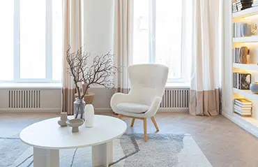 Hell und freundlich eingerichtetes Altbau-Wohnzimmer mit zweiflügeligen Wohnzimmerfenstern.