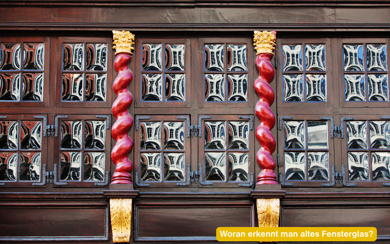 Woran erkennt man altes Fensterglas? Historische Fassade mit alten Scheiben und welligen Spiegelungen