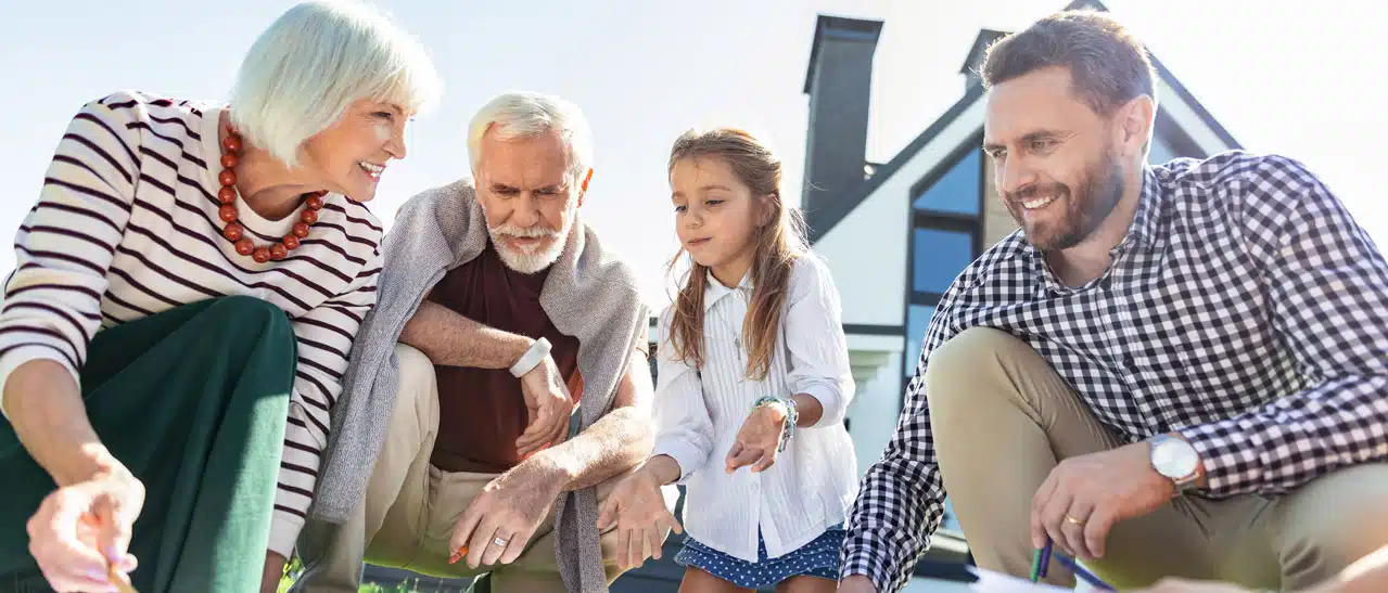 Familie plant im Garten bei schönem Wetter das Aufstocken oder den Anbau für Zwei-Generationen unter einem Dach