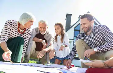 Familie bespricht bei schönem Wetter im Garten den Plan für das Aufstocken oder den Anbau für Zwei-Generationen unter einem Dach.