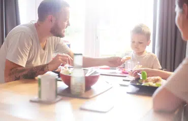 Junge Familie sitzt vor einem Fenster von Schmidinger und genießt den Tag, da der Zwickeltag geschlossen ist.